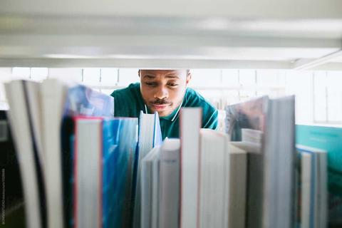 male student browsing library bookshelf 